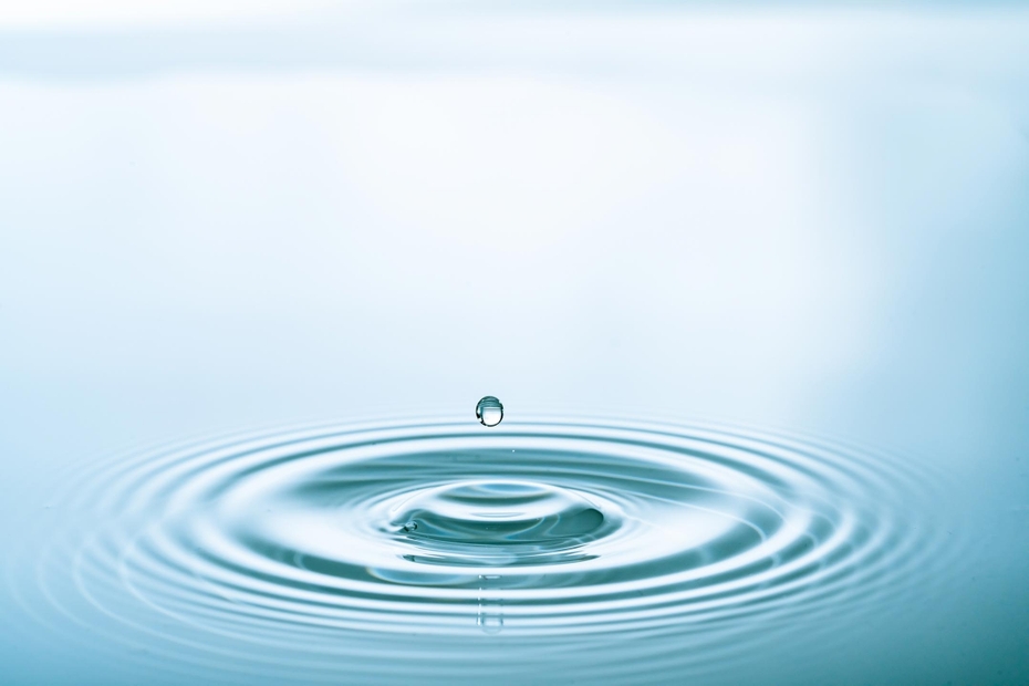 A water droplet lands and causes ripples in water.